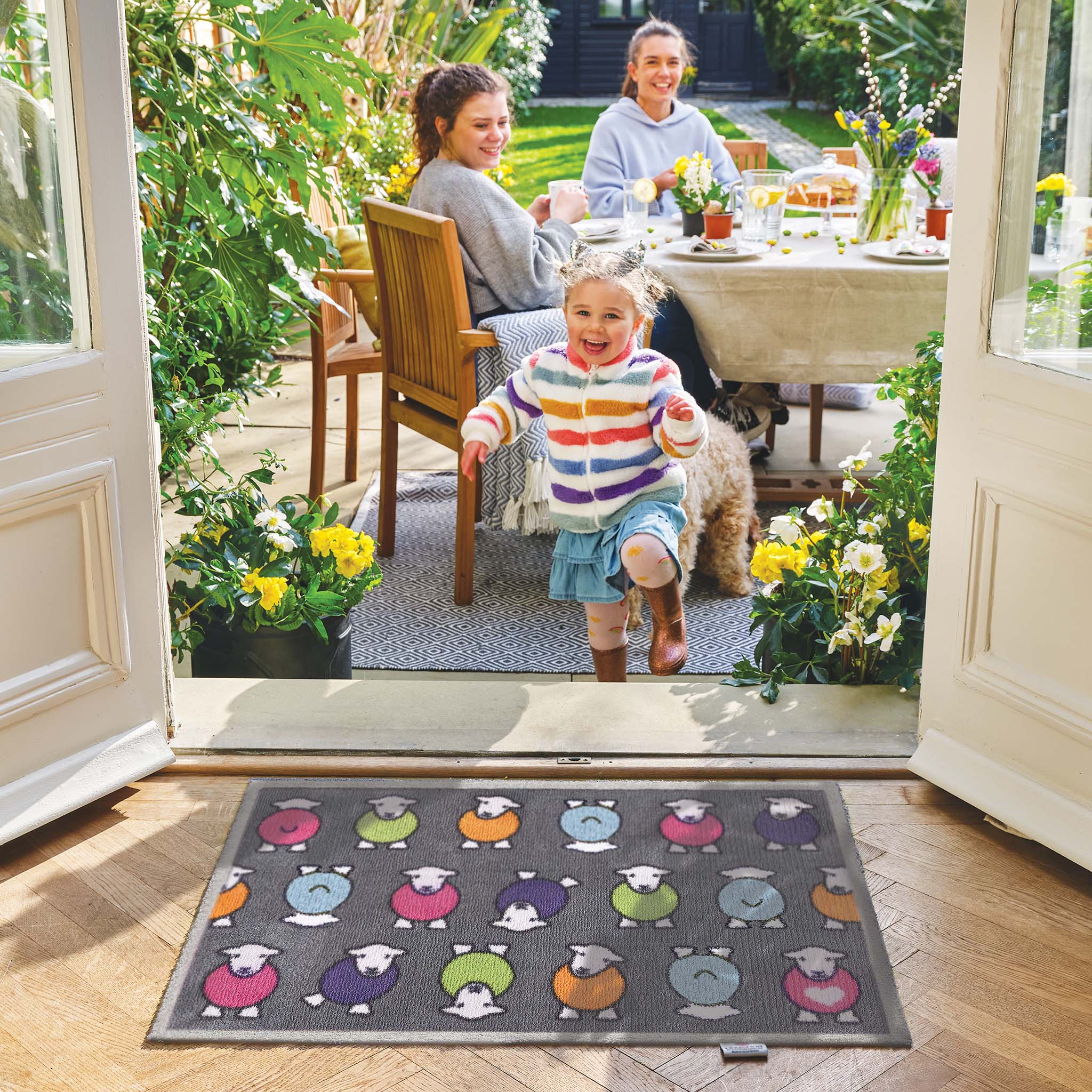 Lifestyle image of a young girl standing in front of a grey marra Herdy washable indoor doormat from Hug Rug