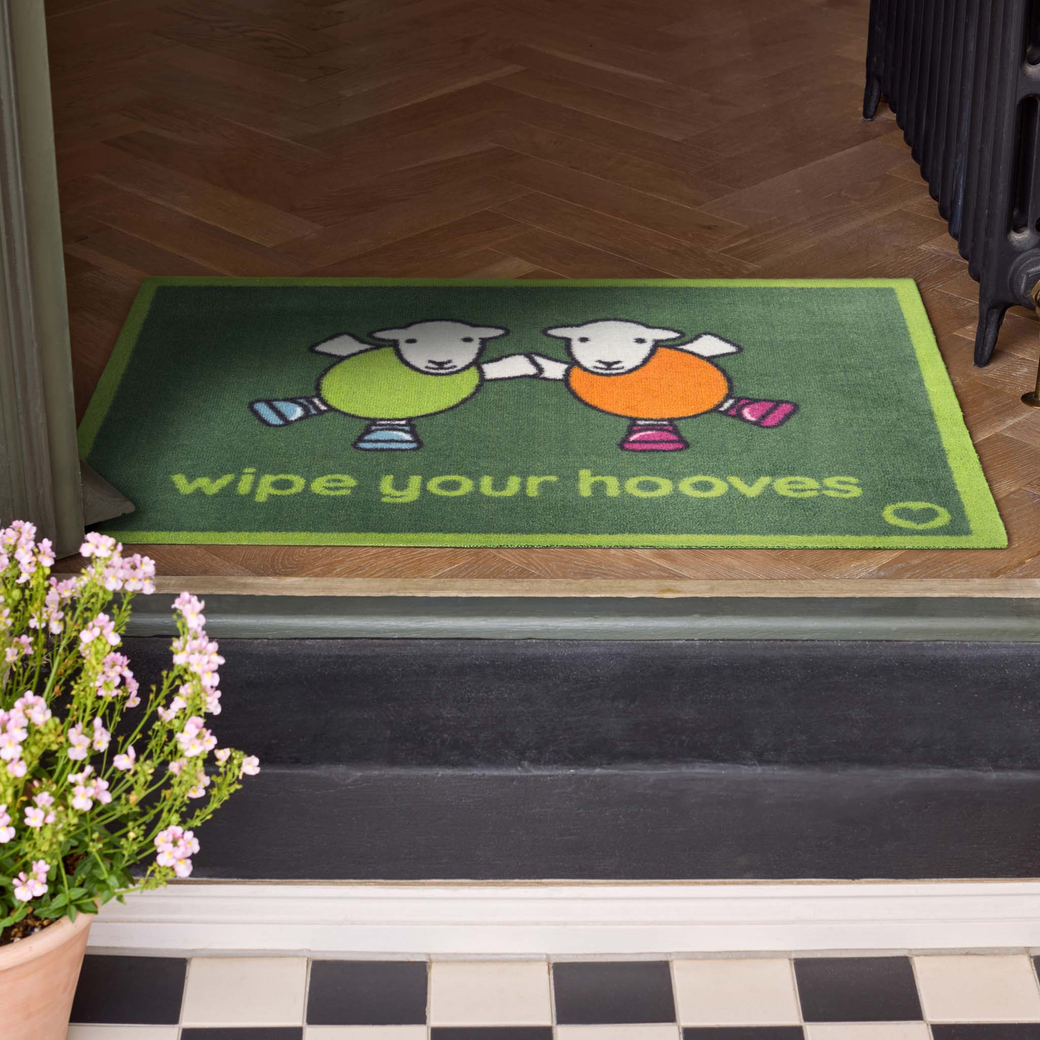 Herdy Wipe Your Hooves Green Doormat with a fun herdy design, styled in a doorway.