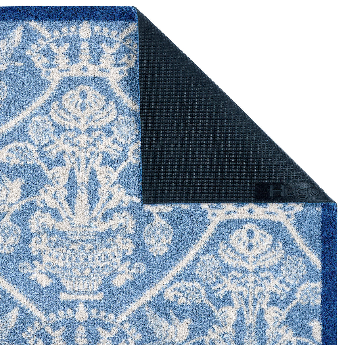 Close-up of the Highgrove Damask Tetbury Blue Washable Runner with a blue traditonal styled pattern showing the rubber backing. 
