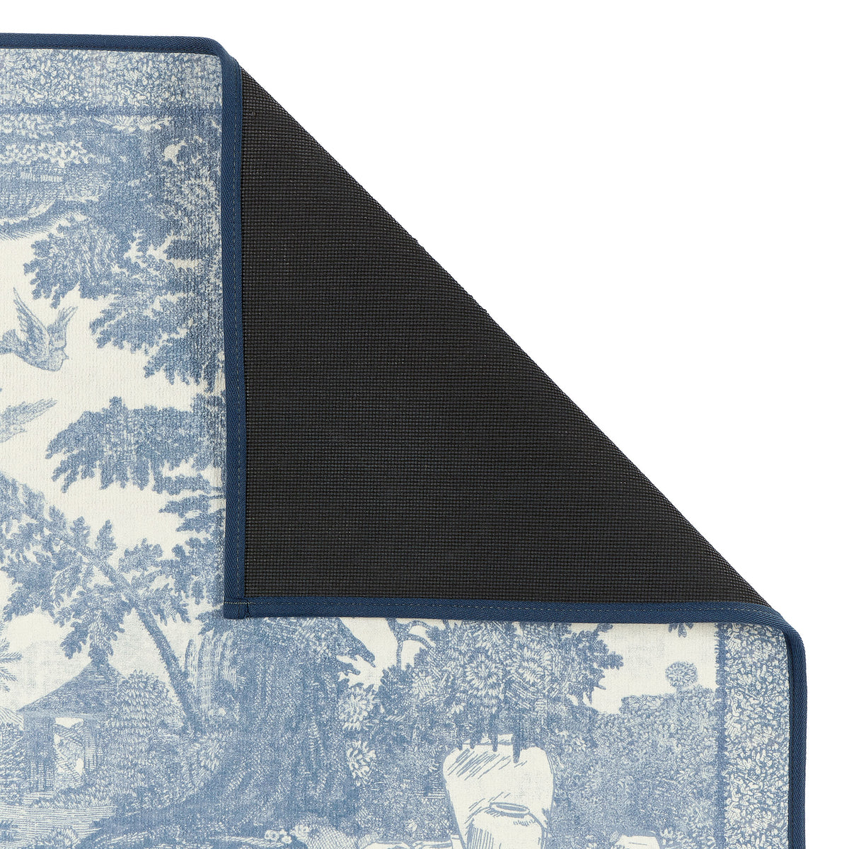 Close-up of The Highgrove Toile Tetbury Blue Eco-Washable showing a blue and white nature inspired pattern with a rubber backing. 