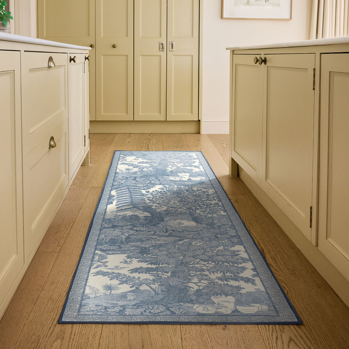 Highgrove Toile Tetbury Blue Eco-Washable Runner with a blue and cream nature inspired pattern, styled on wooden flooring. 
