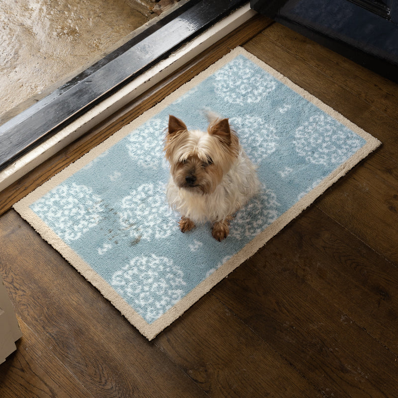 Home 15 Blue Washable Doormat with a white floral design, styled in a doorway.