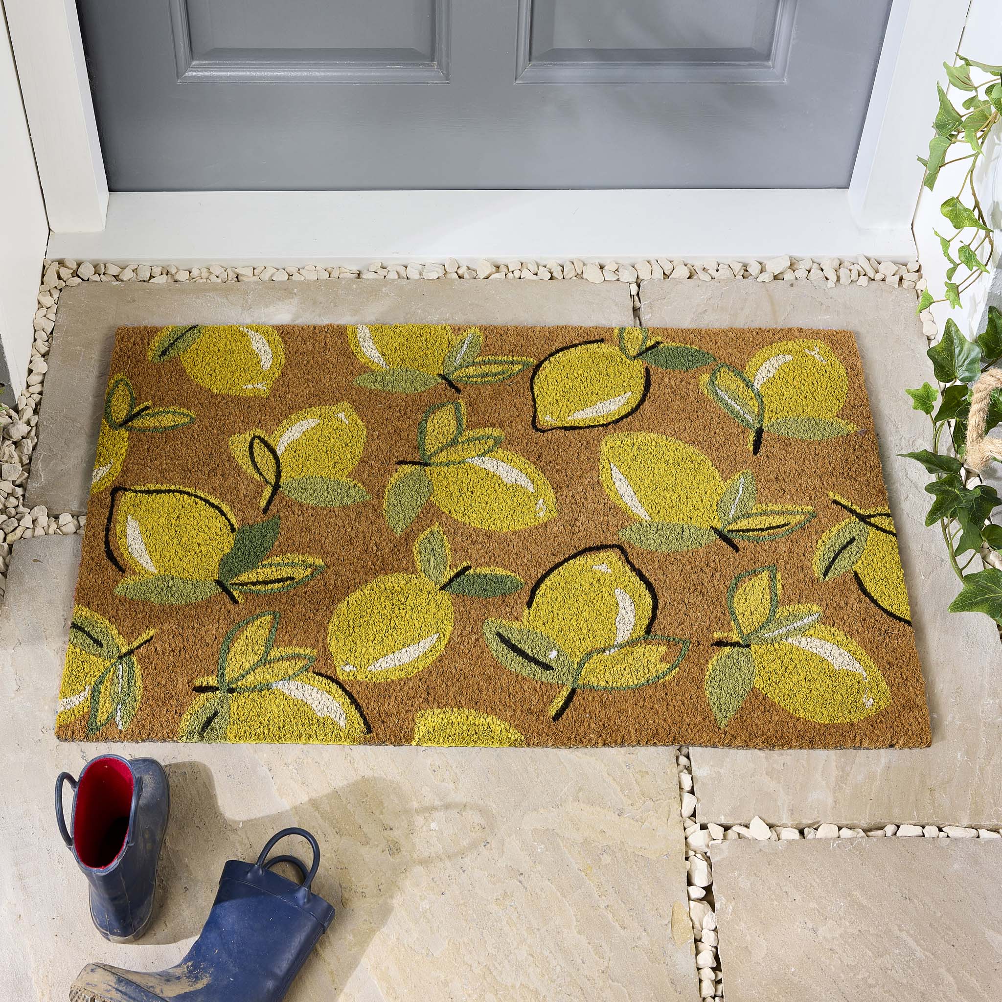 Lemons Yellow Coir Doormat with a multi-directional lemon pattern, styled in a doorway.