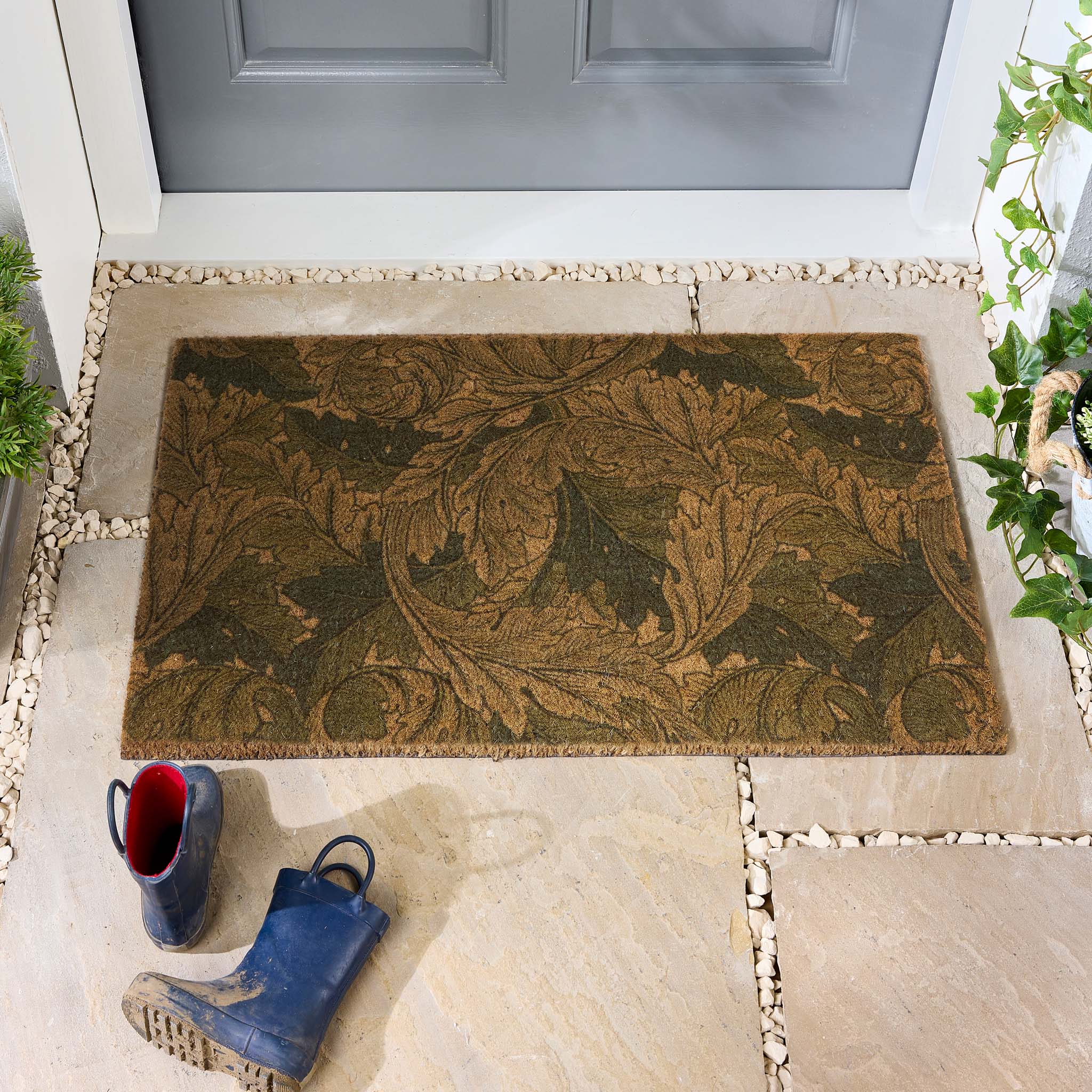 Morris & Co. Acanthus Green Coir Doormat with a leaf pattern, styled in a doorway.
