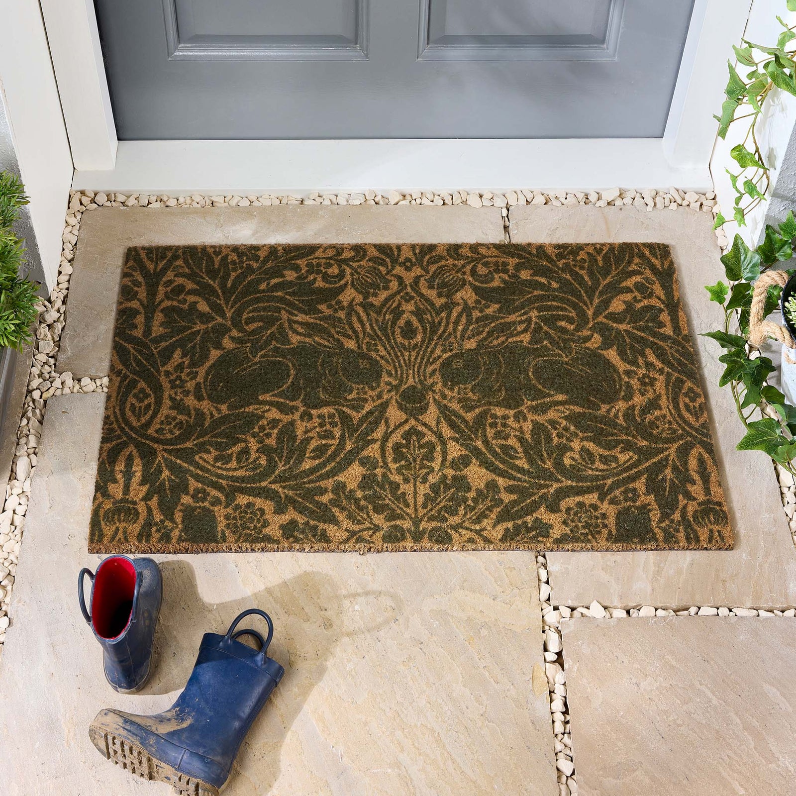 Morris & Co. Brer Rabbit Green Coir Doormat with a nature inspired pattern, styled in a doorway.