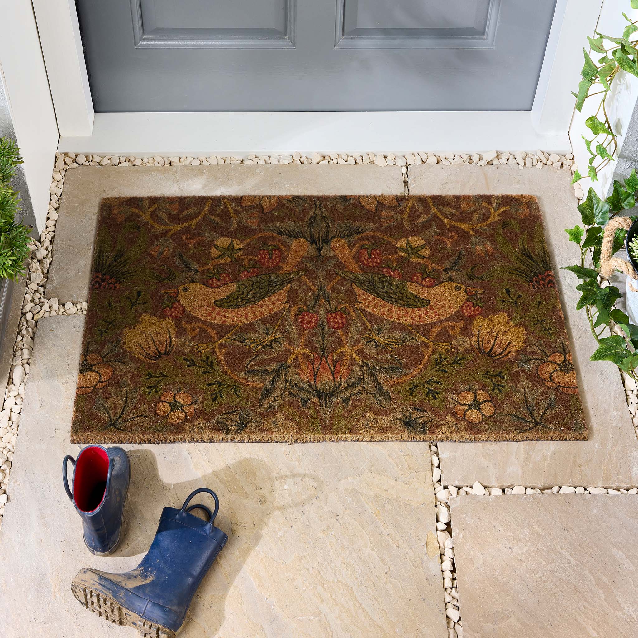 Morris & Co. Stawberry Thief Red Coir Doormat with a nature inspired pattern, styled in a doorway.