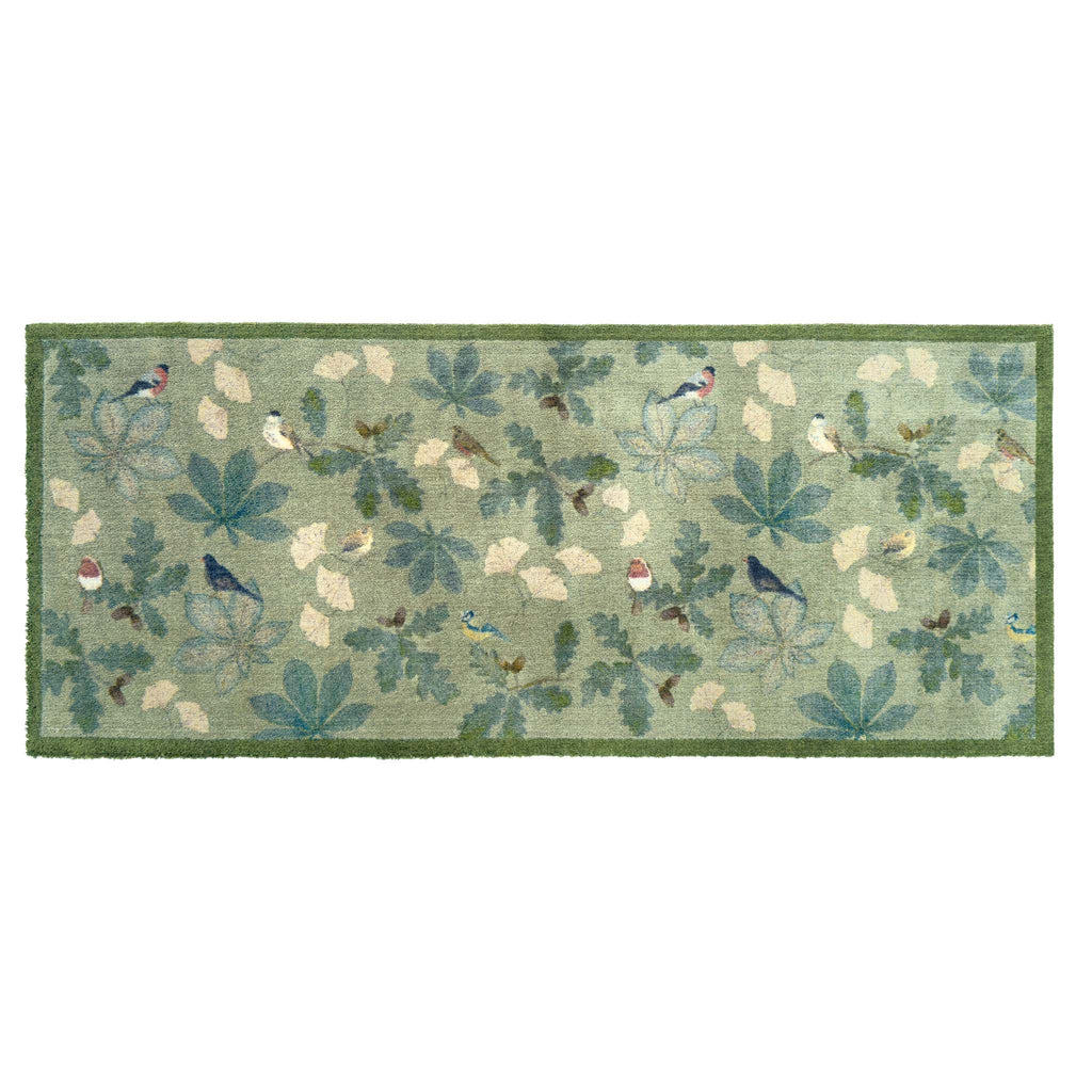 A rectangular area runner with a woodland pattern featuring blue birds, green leaves, and cream-colored acorns on a sage green background, finished with a solid green border.