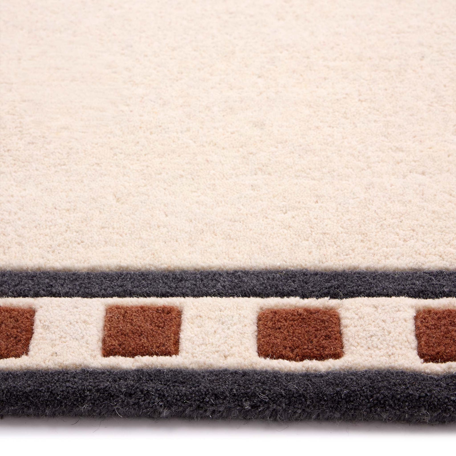 Borderline Natural Rug- a 100% wool cut pile rug featuring a brown and black geometric border. 