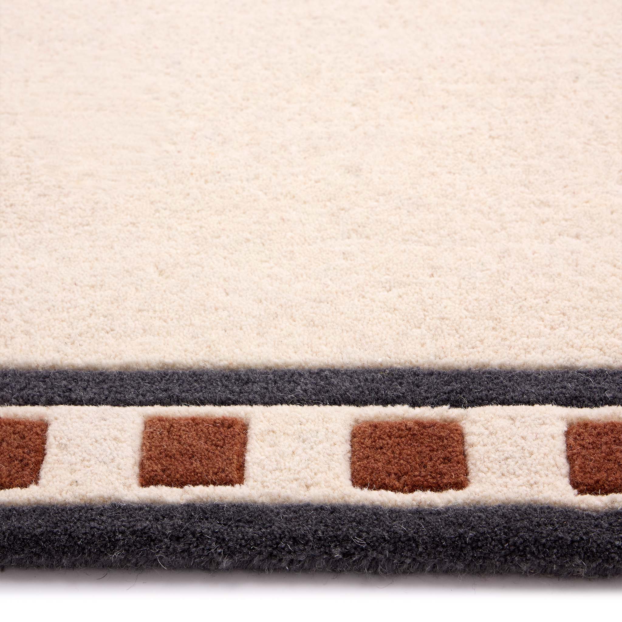 Borderline Natural Rug- a 100% wool cut pile rug featuring a brown and black geometric border. 