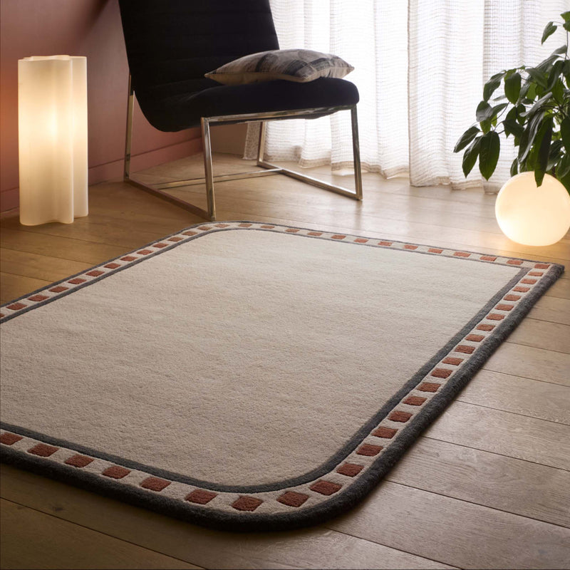Borderline Natural Rug- a 100% wool cut pile rug featuring a brown and black geometric border. 
