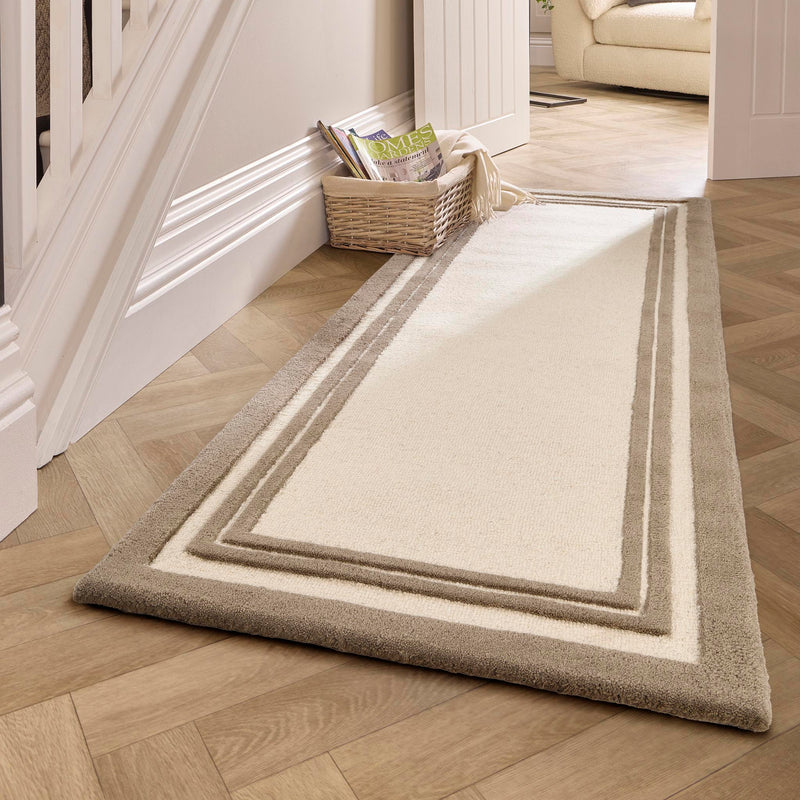 Piper Taupe Wool Rug with a thick brown border followed by two thinner borders, styled by the stairs. 