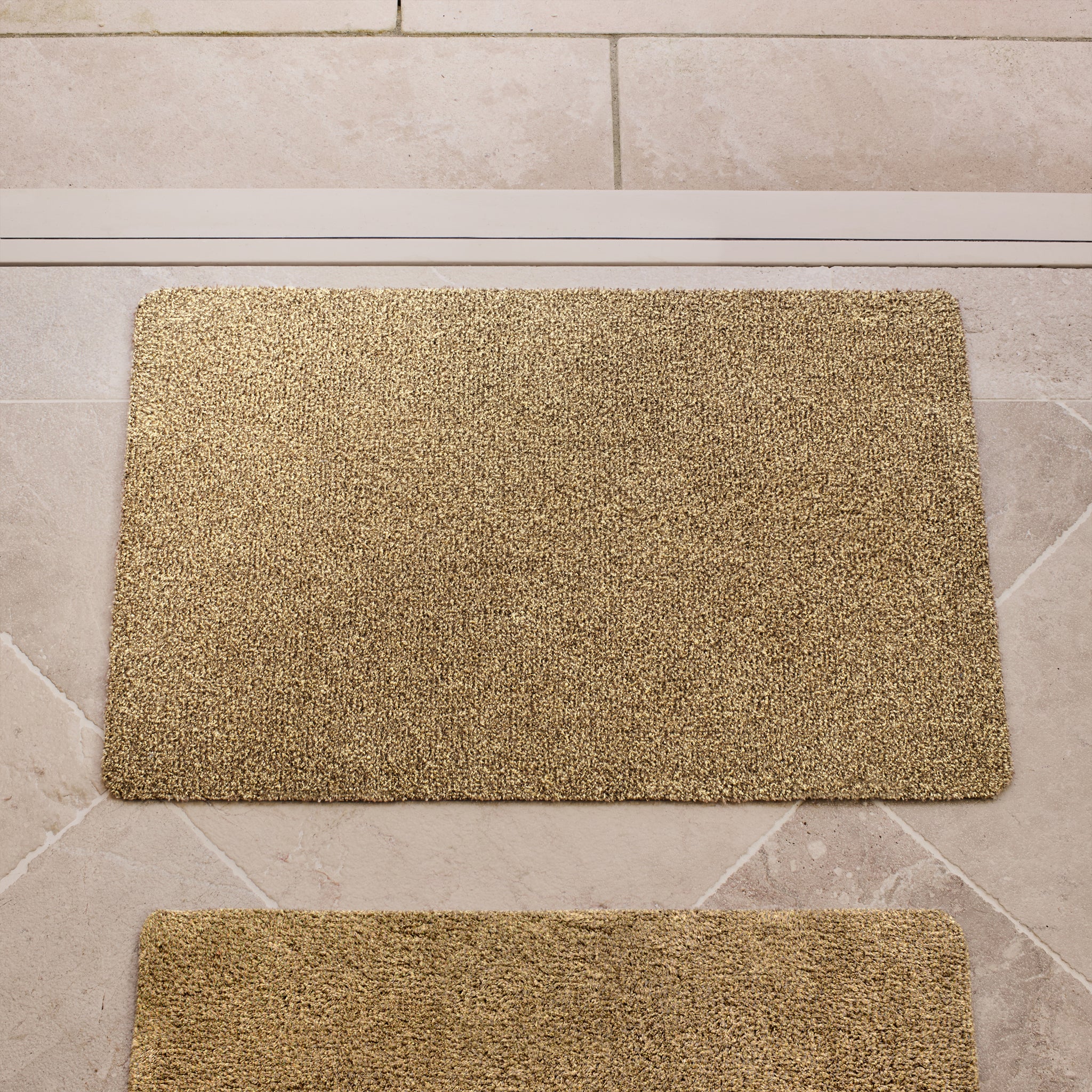 Plain Fleck Stone Cotton Doormat in a light brown colour, styled in a doorway.