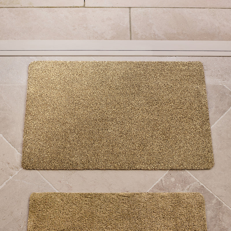 Plain Fleck Stone Cotton Doormat in a light brown colour, styled in a doorway.