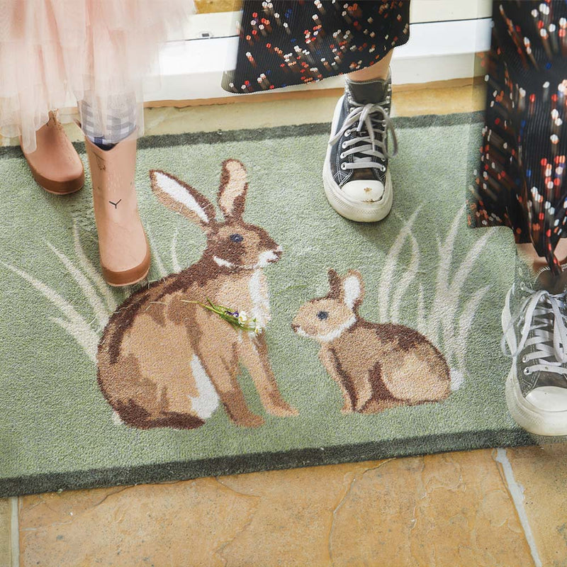 Rabbit 1 Green Washable Doormat made from 100% recycled materials, featuring two rabbits sitting in the green reeds.