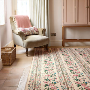 Rose Pergola Chintz Eco-Washable Rug with a floral design, styled by a armchair. 