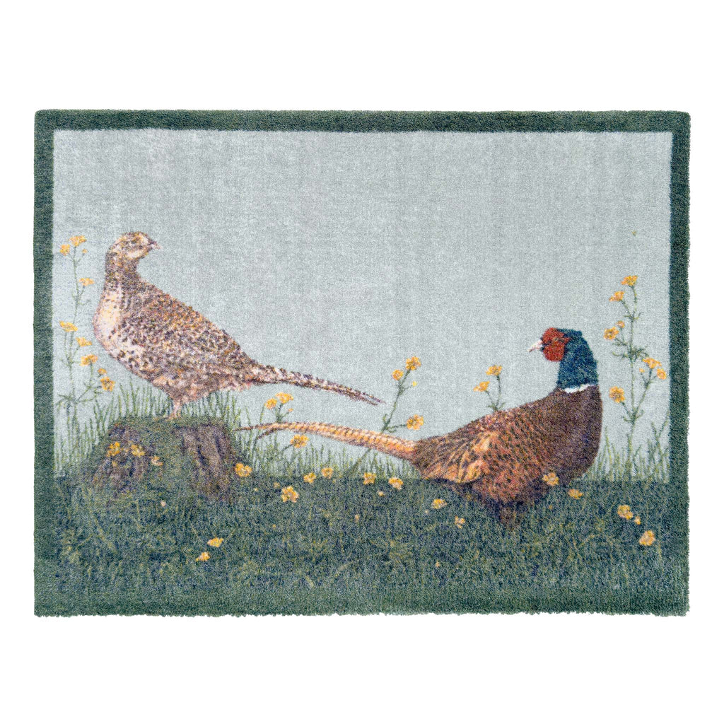A rectangular doormat featuring two pheasants in a grassy field with small yellow flowers, set against a light gray background with a dark green border.