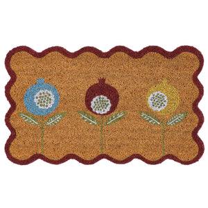 A rectangular coir doormat with a scalloped dark red border and three stylized flower motifs in blue, brown, and yellow on a natural background.