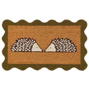A rectangular coir doormat with a scalloped dark green border and a central design of two facing hedgehogs on a natural background, isolated on a white backdrop.