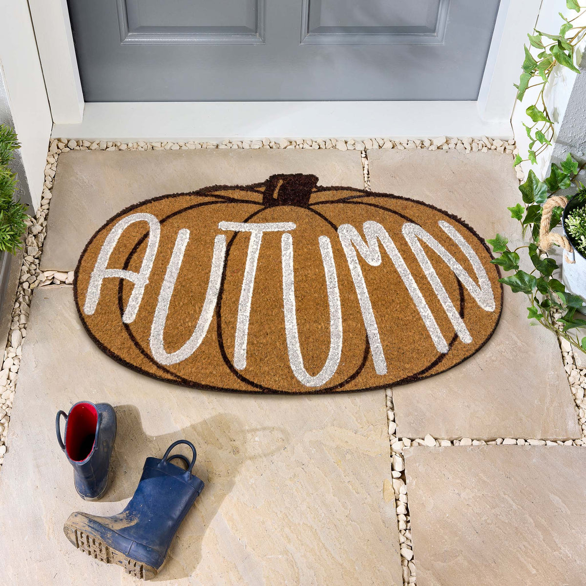 Shaped Autumn Pumpkin Coir Doormat, styled on stone flooring.