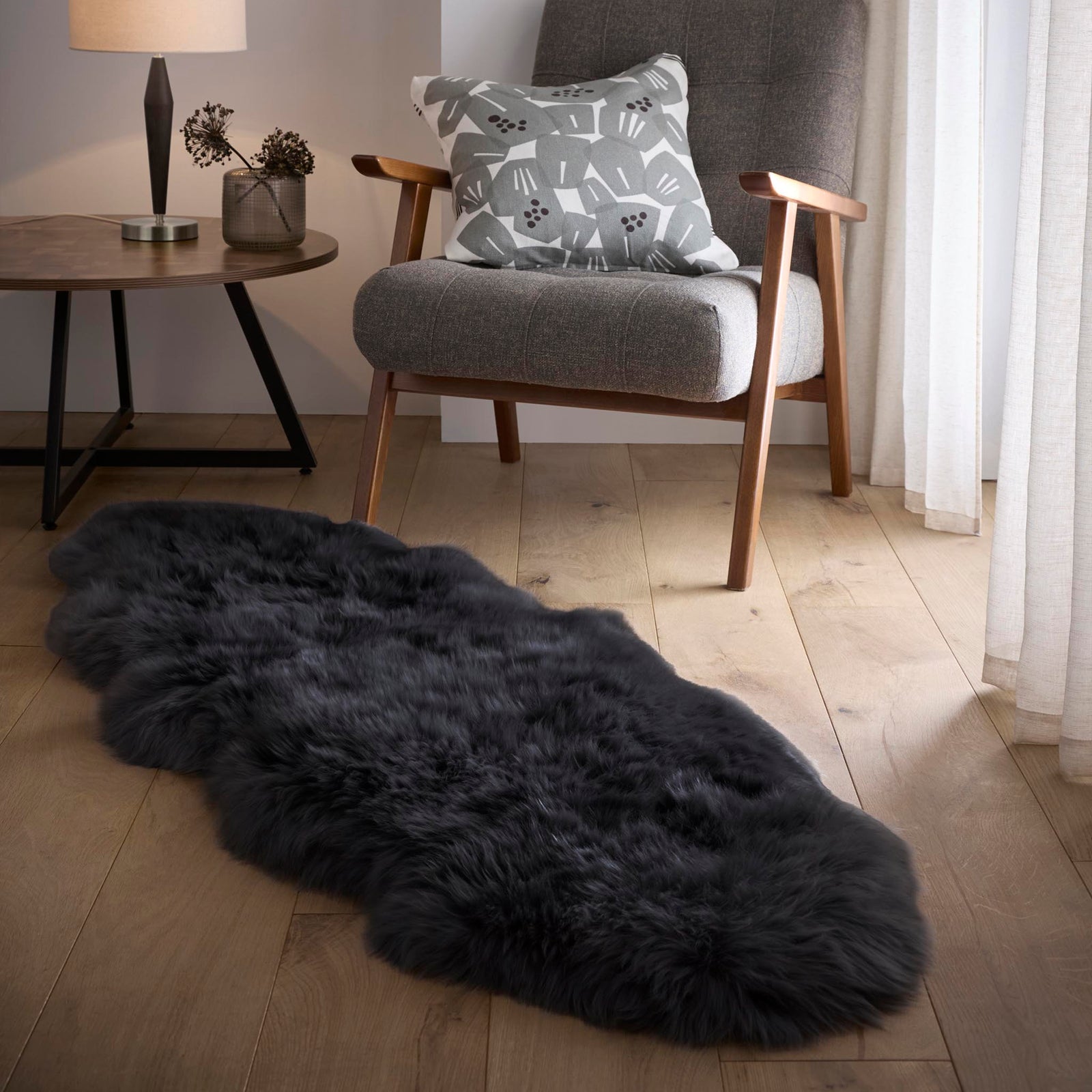 Double Sheepskin Black Rug made up of long-haired wool, styled on wooden flooring.