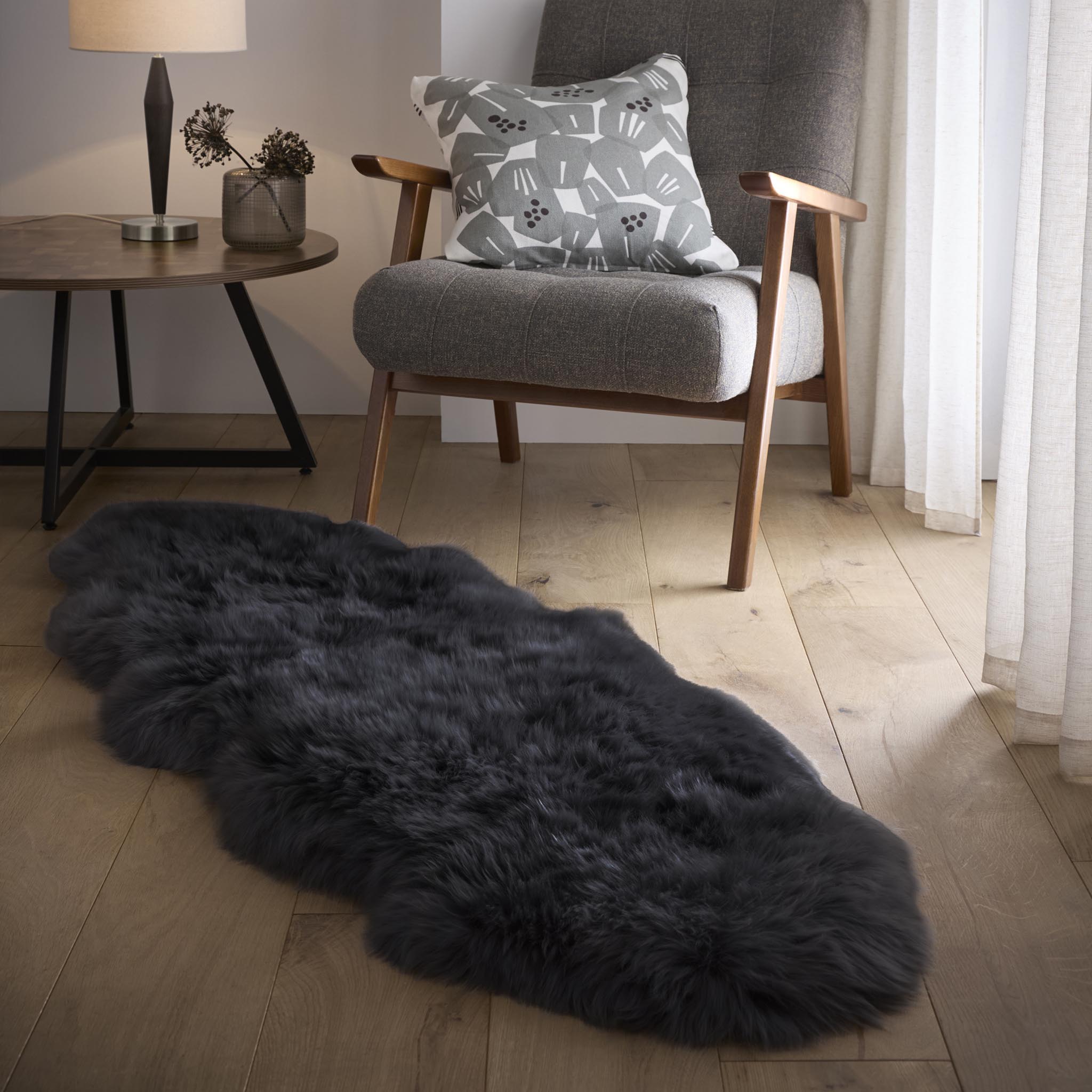 Double Sheepskin Black Rug made up of long-haired wool, styled on wooden flooring.