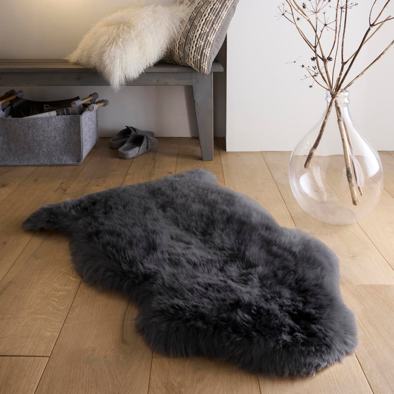 Single Sheepskin Black Rug made up of long-haired wool, styled on wooden flooring.