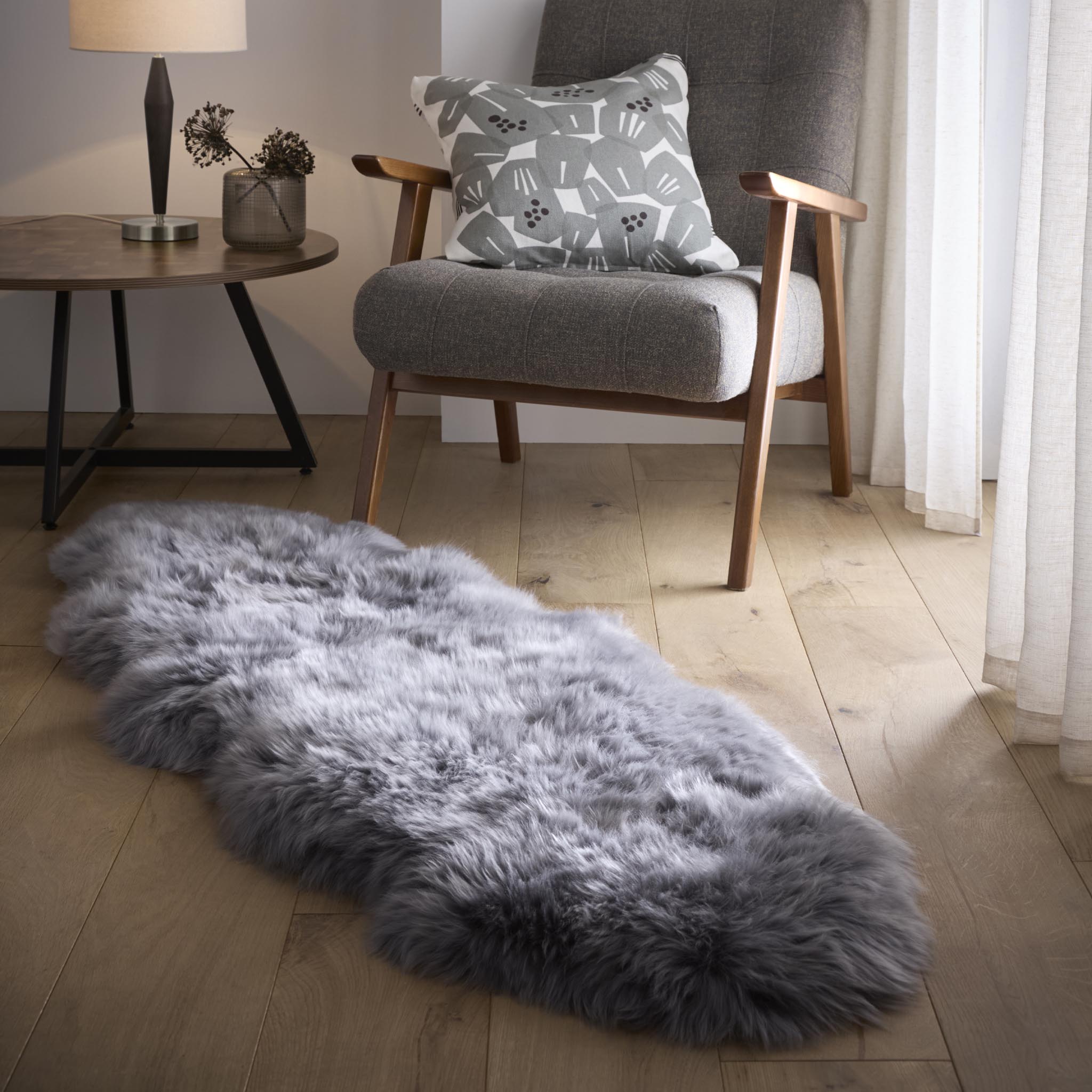 Double Sheepskin Grey Rug made from long-haired wool, styled on wooden flooring.