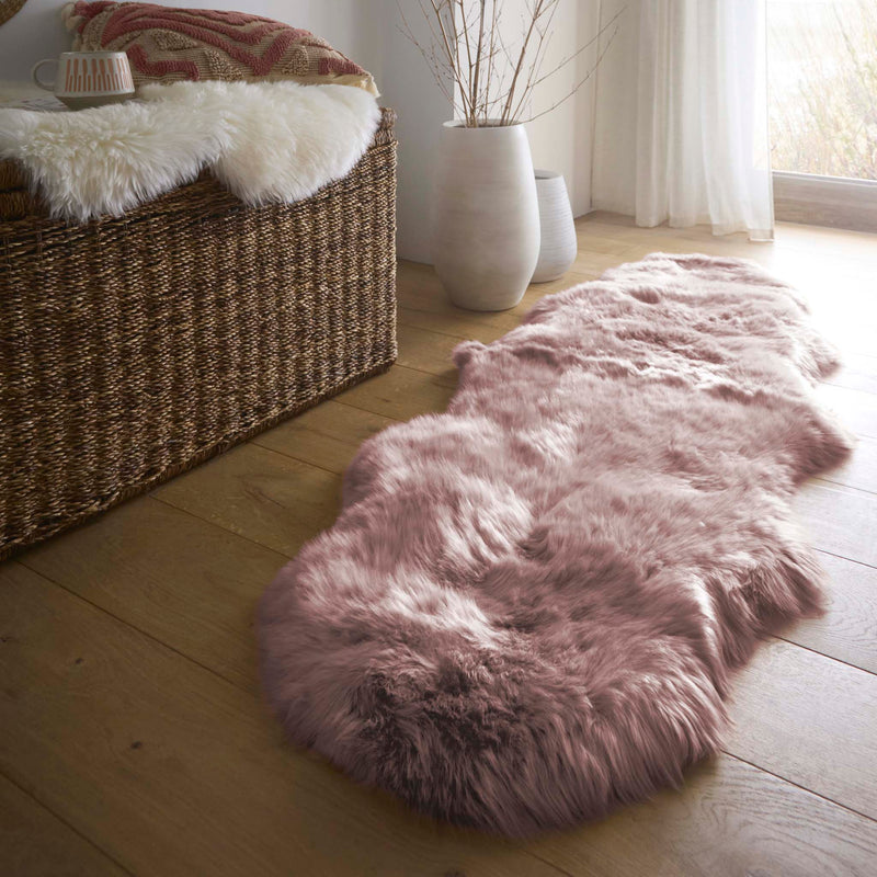 Double Sheepskin Rose Pink Rug made from long-haired wool, styled on wooden flooring.