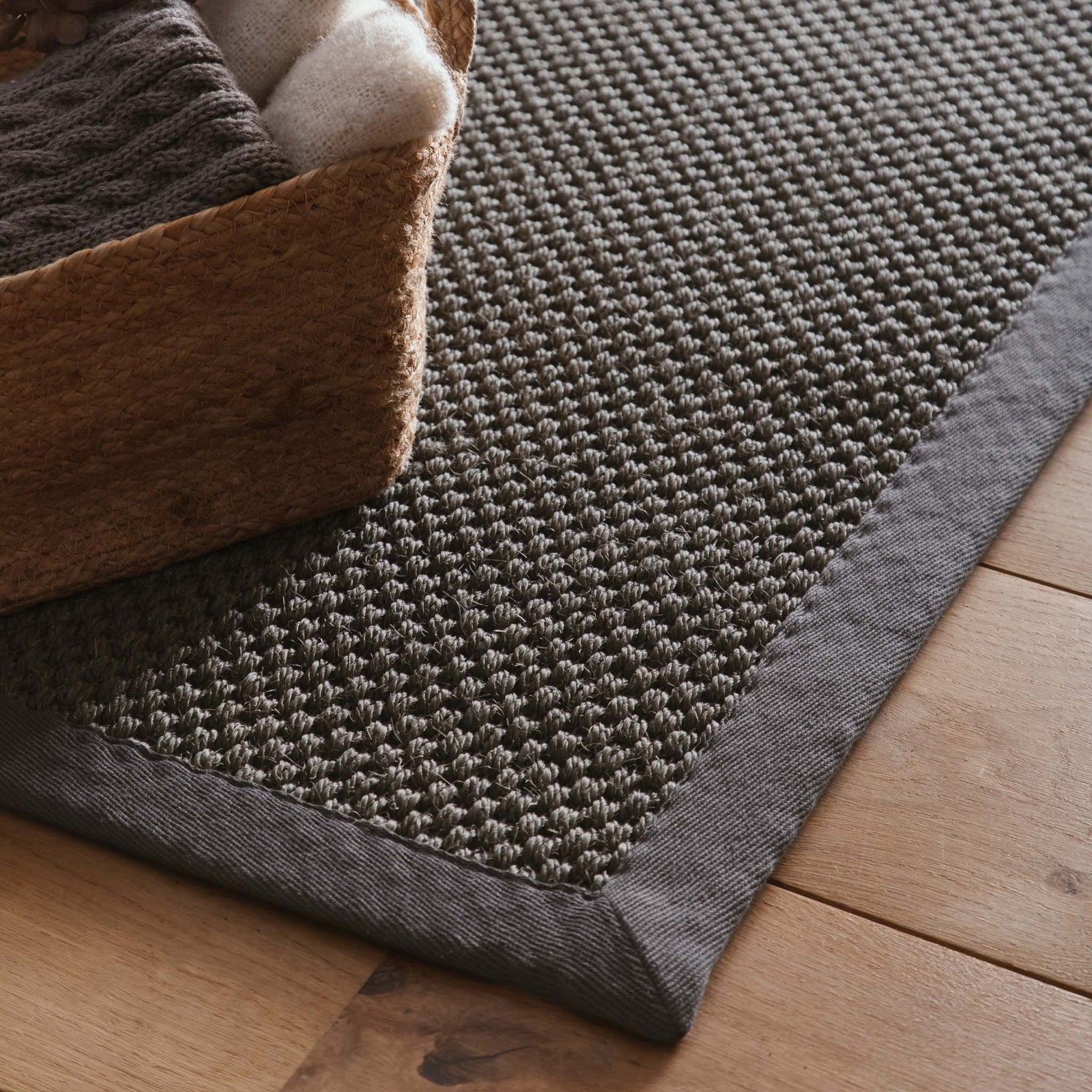 Close-up of Sisal Grey with Dark Grey Border Rug, styled on wooden flooring.