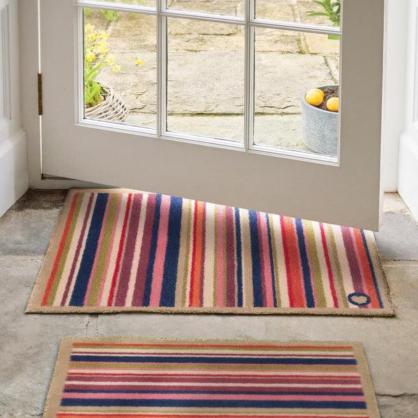 Sunset Stripe Washable Doormat- a wool washable doormat featuring a cheerful mix of stripes in pink, green, white , orange ,blue and purple. 