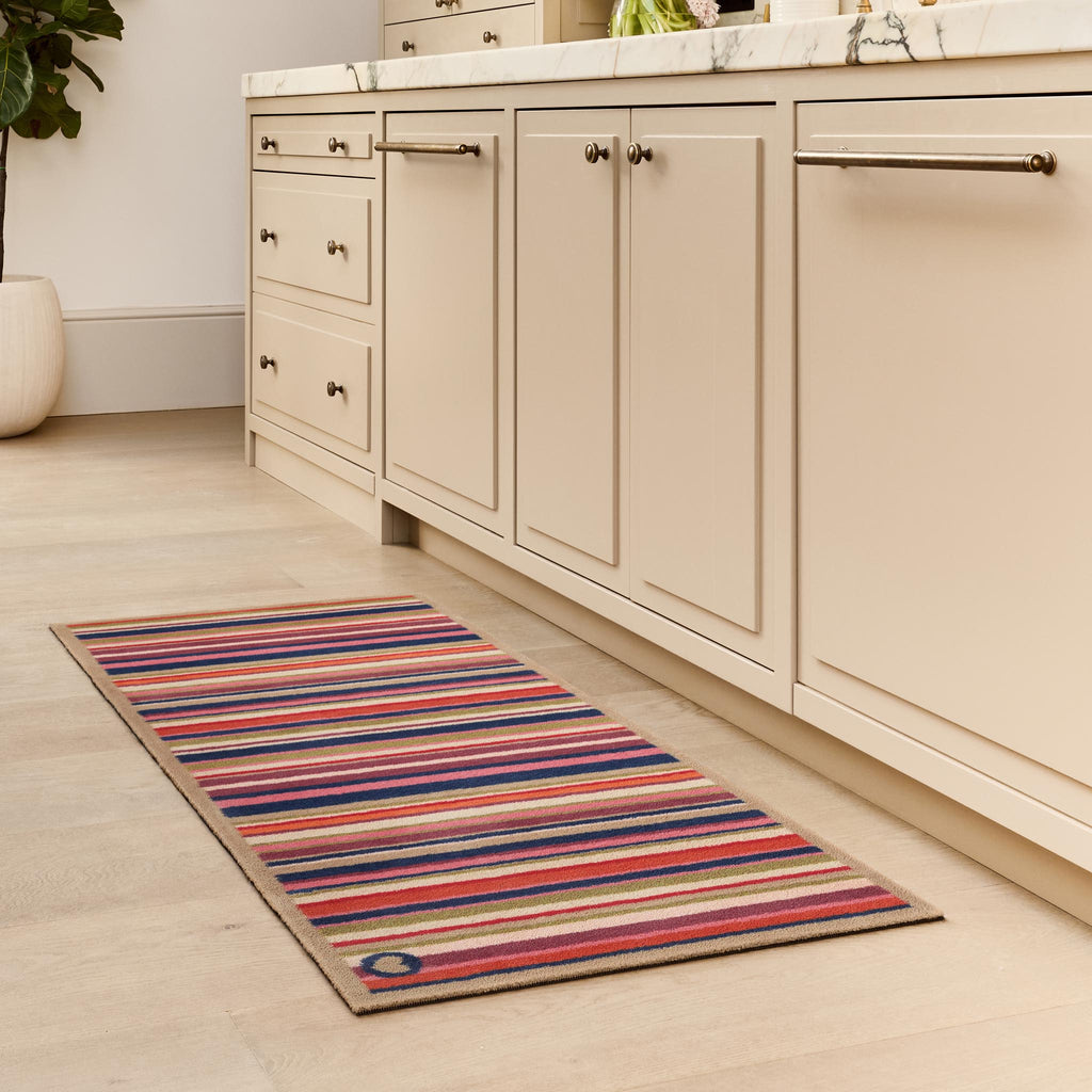 Sunset Stripe Washable Doormat- a wool washable runner featuring a cheerful mix of stripes in pink, green, white , orange ,blue and purple. 