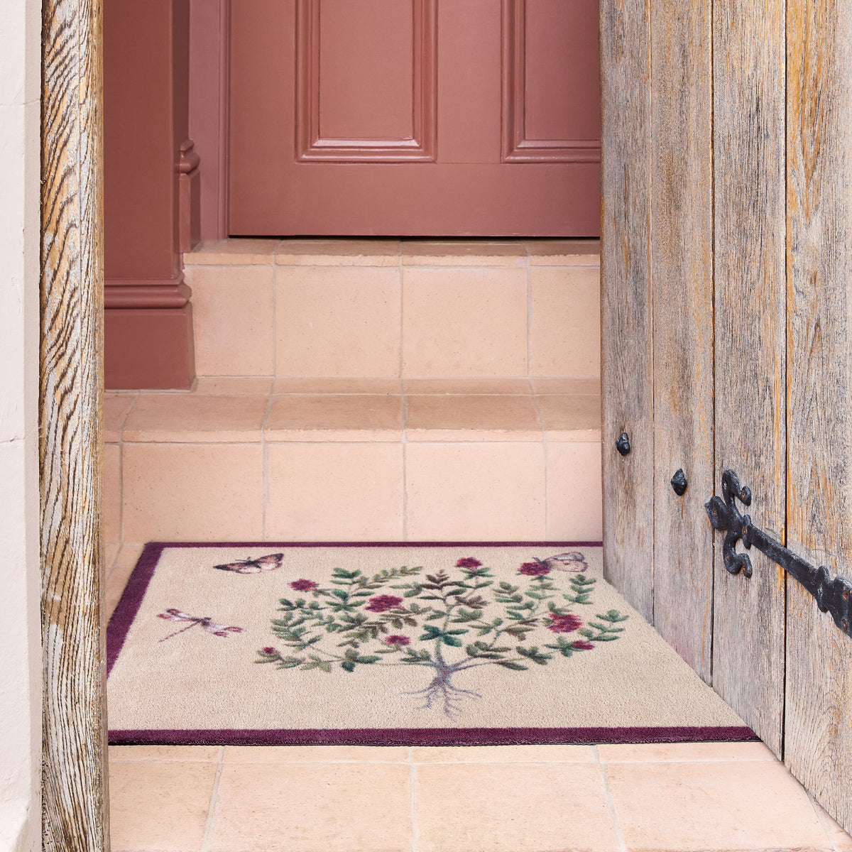 Thyme Walk Lichen & Gooseberry Washable Doormat with a purple floral nature inspired pattern, styled on tile steps.