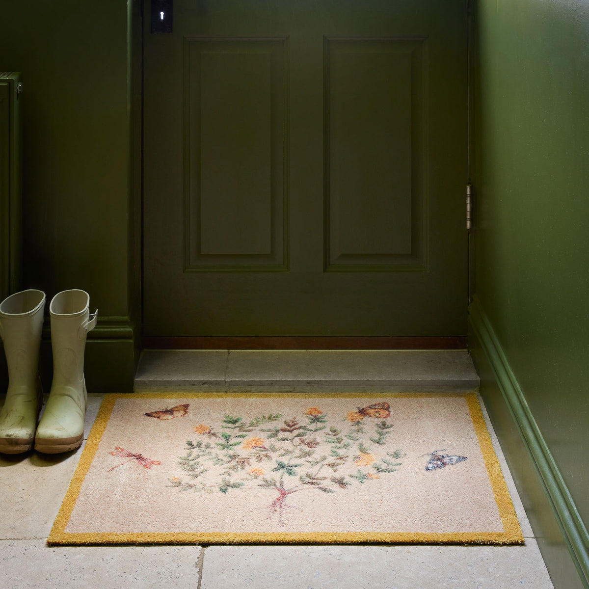 Thyme Walk Lichen & Gooseberry Washable Doormat with a yellow floral nature pattern , styled on stone floooring.