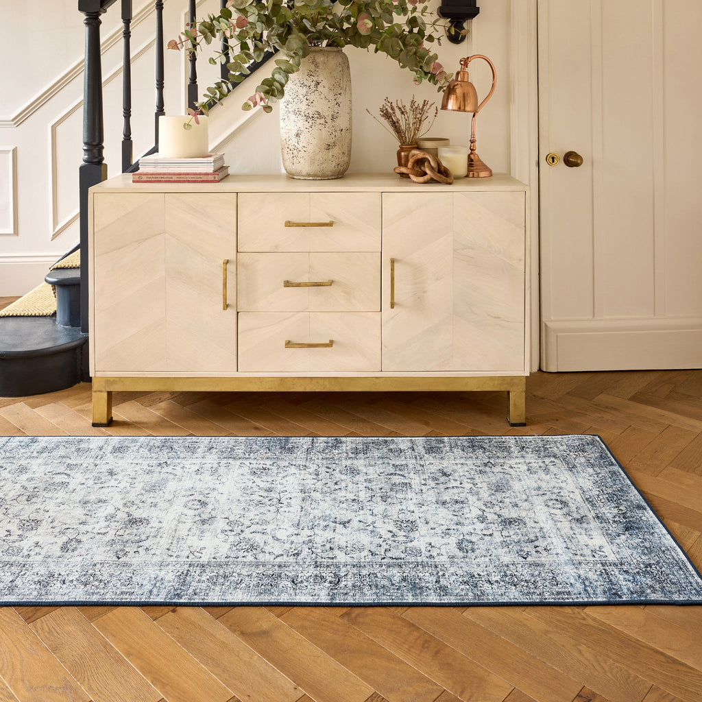 Hallway showing a runner in a vintage blue and grey pattern on wooden floor with a cabinet in the background 