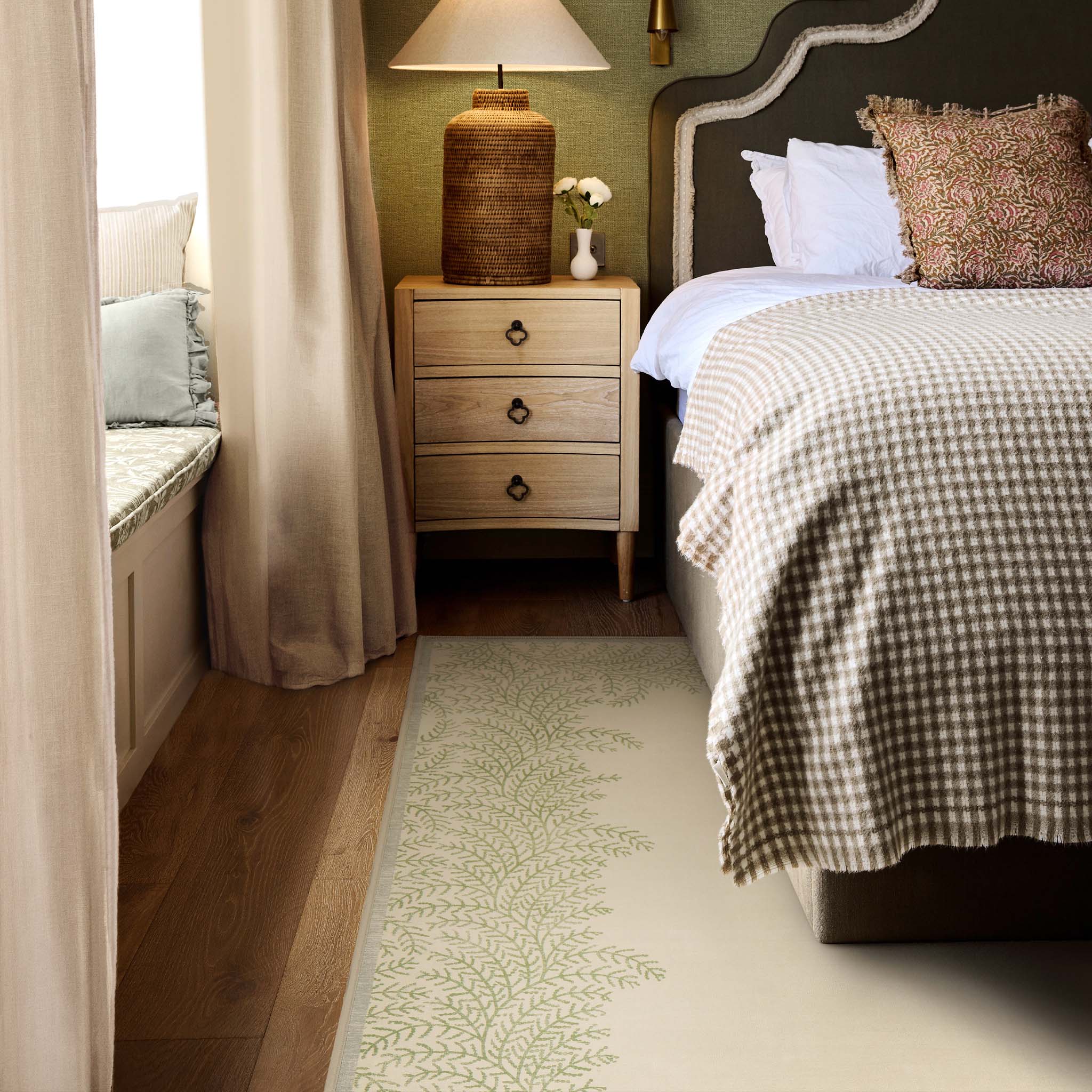 Whispering Fern Parchment Eco-Washable Rug with a fern leaf border design, styled under a bed. 
