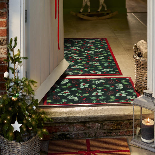 Discover the Winter Berries Doormat- a cotton mat featuring pinecones, red berries and holly leaves. 